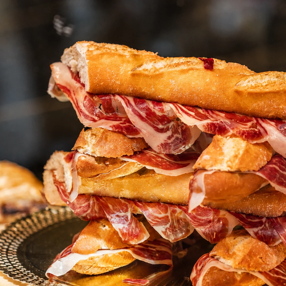 Hamburguesa gourmet con queso fundido, bacon crujiente y rúcula sobre pan brioche.